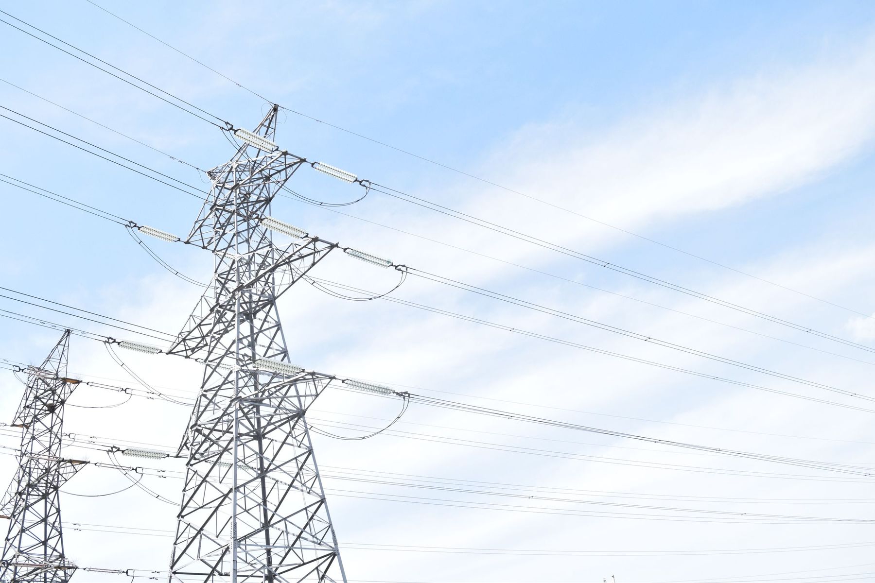 High-voltage transmission pylons and power lines against a pale blue sky