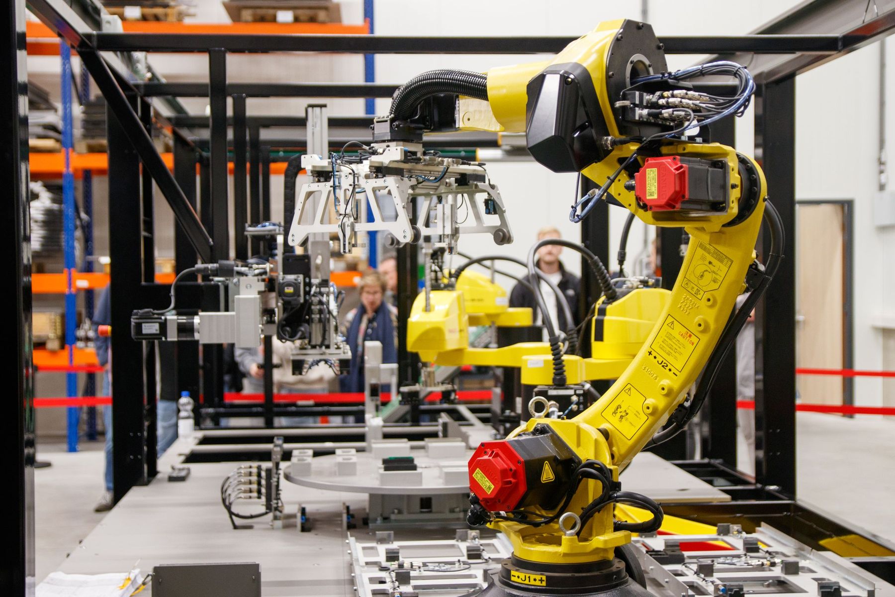 Yellow industrial robot arms working in an automated assembly cell in a bright factory hall